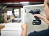 A person is using a cordless drill to attach a cabinet hinge in a workshop setting. Produktbild-Vorschau