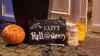 Halloween decorations on a doorstep, including a pumpkin, a chalkboard sign, and lanterns. Produktbild-Vorschau