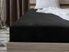 A close-up view of a black fitted sheet on a bed. Náhled obrázku produktu