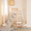 A wooden indoor play structure with a slide, climbing net, and ladder, set up in a room with soft furnishings. Anteprima dell’immagine prodotto