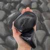 Schwarze glatte Kieselsteine in einer Hand gehalten zur Größenansicht Produktbild-Vorschau