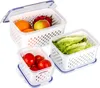 Three clear plastic food storage containers with perforated inserts, filled with various fruits and vegetables, arranged on a white background. Produktbild-Vorschau