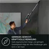 A man is vacuuming a corner near the ceiling with a cordless vacuum cleaner. Produktbild-Vorschau
