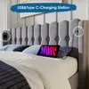 A bed with a gray upholstered headboard, featuring built-in USB and Type-C charging ports, with a tablet charging on the bed. Produktbild-Vorschau