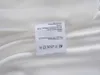 A close-up of a clothing care label attached to a white fabric. Podgląd zdjęcia produktu