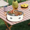 A portable charcoal grill with food on a wooden table outdoors. Anteprima dell’immagine prodotto