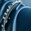 A close-up shot of a beaded hair accessory resting on draped blue velvet fabric. Voir les images du produit