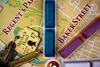 A close-up view of a board game, likely a mystery or detective game, with game pieces and a hotel key tag on a map-like board. Náhľad obrázku produktu