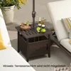 A small outdoor side table with a basket storage, placed on a patio next to a lounge chair. It holds drinks and limes, with an umbrella pole in the center. Podgląd zdjęcia produktu