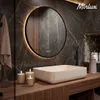 A modern bathroom vanity with a round LED mirror, a rectangular sink, and decorative candles. Produktbild-Vorschau