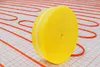 A roll of yellow insulation material for underfloor heating is placed on a grid with orange heating pipes. Náhľad obrázku produktu