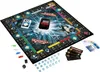 A Monopoly Banking Ultra board game is laid out on a white surface, with game pieces, cards, and a banking unit visible. Produktbild-Vorschau