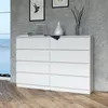 A white dresser with eight drawers is shown in a room with a gray textured wall and a wooden floor. Produktbild-Vorschau