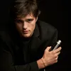A man in a black suit holding a bottle of perfume against a black background. Náhľad obrázku produktu