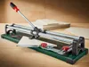 A tile cutter on a wooden surface with tiles in the background. Produktbild-Vorschau