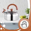 A stainless steel kettle with a wooden handle sits on a kitchen counter in front of a brick wall. Náhled obrázku produktu