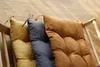 Three cushions are placed on a wooden chair. Produktbild-Vorschau