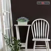 A white chair and a small white table with a potted plant on it, next to a white window frame. Produktbild-Vorschau
