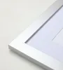 A close-up view of the corner of a silver picture frame with a white mat. Produktbild-Vorschau
