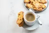 A cup of coffee with biscotti on a white surface. Produktbild-Vorschau