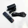 A black remote control, a black power adapter with a European plug, and a black USB cable are laid out on a white surface. Produktbild-Vorschau