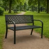A black metal park bench sits on a gravel path in a park with trees and grass. Anteprima dell’immagine prodotto