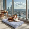 A dog is lying on a dog bed in front of a large window with a city view. Podgląd zdjęcia produktu