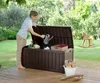 A woman is putting a watering can into a storage box in a garden. Podgląd zdjęcia produktu