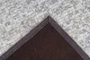A close-up view of the corner of a rug, showing the textured surface and the dark brown backing. Produktbild-Vorschau