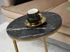 A black marble side table with gold accents, featuring a black and gold coffee cup and saucer. Anteprima dell’immagine prodotto