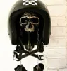 A motorcycle helmet with a skull decoration and tools hanging from it. Produktbild-Vorschau