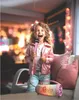 A young girl is singing into a pink microphone while sitting on a couch, with a colorful, illuminated speaker in front of her. Voir les images du produit