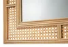 A close-up view of a rattan mirror frame, showing the intricate weaving pattern and the reflective surface of the mirror. Podgląd zdjęcia produktu