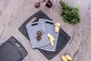 A set of cutting boards with some ingredients on them, arranged on a wooden surface. Produktbild-Vorschau