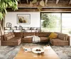 A spacious living room with a large sectional sofa, a coffee table, and a large window overlooking greenery. Produktbild-Vorschau