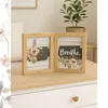 A wooden double photo frame with floral designs and the word 'Breathe' is displayed on a light-colored surface. Produktbild-Vorschau