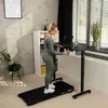 A woman is using a treadmill while working at a standing desk in a home office. Produktbild-Vorschau