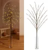 A split image showing a decorative LED twig with warm white lights. The left side shows the twig in a vase on a wooden floor with a wooden crate and decorative balls in the background. The right side shows the twig in a vase against a white background. Produktbild-Vorschau