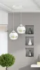 A modern interior scene with two pendant lights hanging from the ceiling, a decorative plant, and recessed shelves with decorative objects. Produktbild-Vorschau