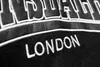 A close-up of black fabric with white embroidered text. Produktbild-Vorschau