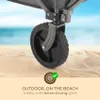 Close-up of a trolley wheel on a sandy beach with the ocean in the background. Produktbild-Vorschau