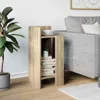 A wooden side table with books and a cup of coffee next to a grey sofa. Náhľad obrázku produktu