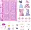 A collection of Barbie doll clothes and accessories laid out on a white background, with a pink doll wardrobe in the background. Produktbild-Vorschau
