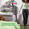 A woman is holding a storage bag with a duvet inside, next to a bed with bedding. Produktbild-Vorschau