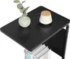 A close-up shot of a black C-shaped side table with a vase of greenery and a mug on top, and books on the lower shelf. Náhľad obrázku produktu