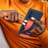 A person holding a dark blue phone case with a red and black strap attached. Náhľad obrázku produktu