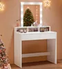 A white vanity table with LED lights and makeup is set up in a festive Christmas setting with decorated trees. Produktbild-Vorschau