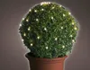A spherical topiary bush decorated with warm white LED lights in a terracotta pot. Produktbild-Vorschau