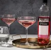 A bottle of rosé wine and two glasses of rosé wine are arranged on a golden tray. Produktbild-Vorschau