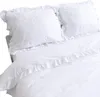A white duvet cover and pillowcases with ruffles are laid out on a bed. Podgląd zdjęcia produktu